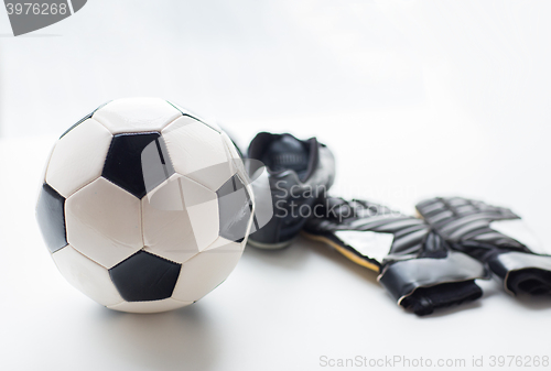 Image of close up of soccer ball, boots and gloves on table