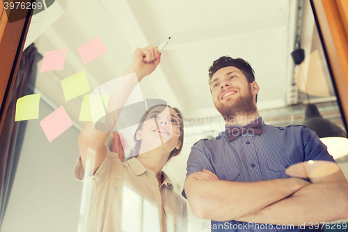 Image of happy creative team writing on blank office glass