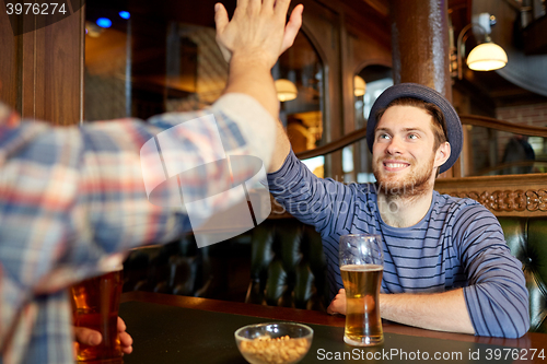 Image of happy male friends making high five at bar or pub