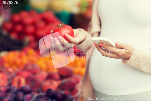 Image of pregnant woman with smartphone at street market