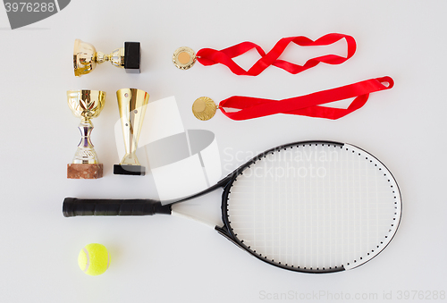 Image of close up of tennis racket, ball, cups and medals