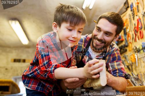 Image of father and little son with wood plank at workshop