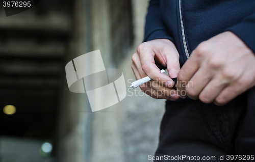 Image of close up of addict hands with marijuana joint