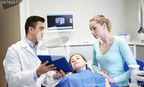 Image of dentist showing tablet pc to girl and her mother