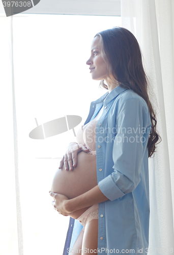 Image of happy pregnant woman with big bare tummy at home