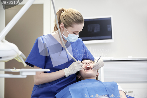 Image of female dentist checking patient girl teeth