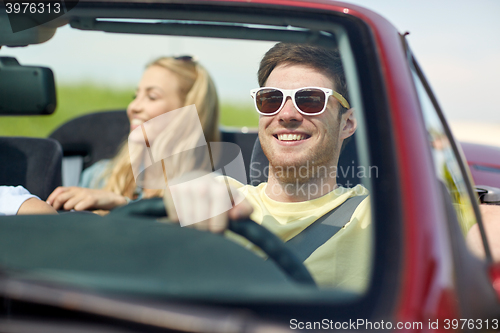 Image of happy friends driving in cabriolet car