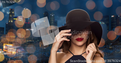 Image of beautiful woman in black hat over night city