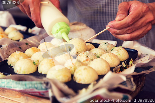 Image of cook stuffing dough or rice balls at street market