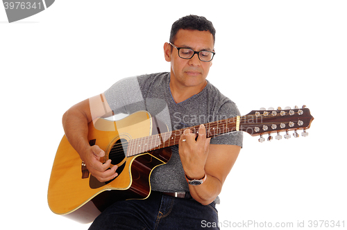 Image of Middle age man playing his guitar.