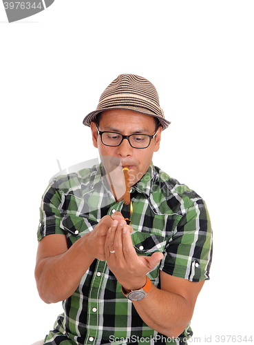 Image of Hispanic man lightning his cigar.