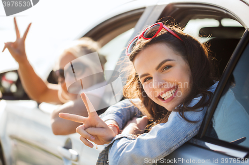 Image of happy teenage girls or women in car at seaside