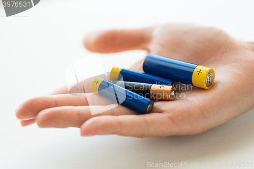 Image of close up of hands holding alkaline batteries heap