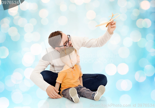 Image of father and little son playing with toy airplane