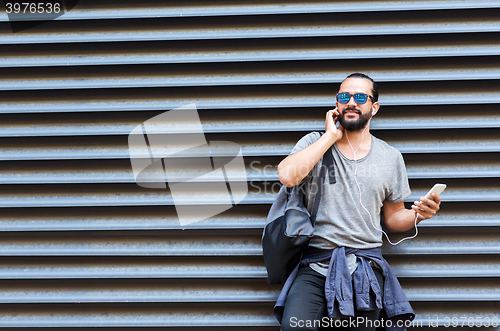 Image of man with earphones and smartphone on city street