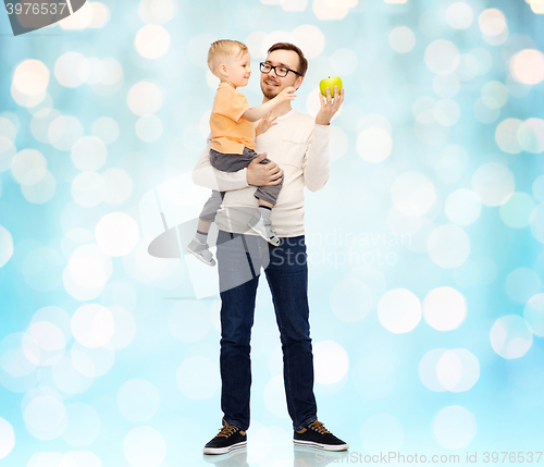Image of happy father and little son with green apple