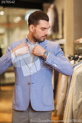 Image of young man trying jacket on in clothing store