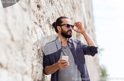 Image of man with smartphone at stone wall