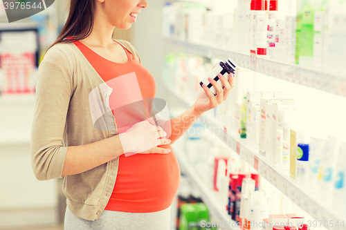 Image of happy pregnant woman with medication at pharmacy