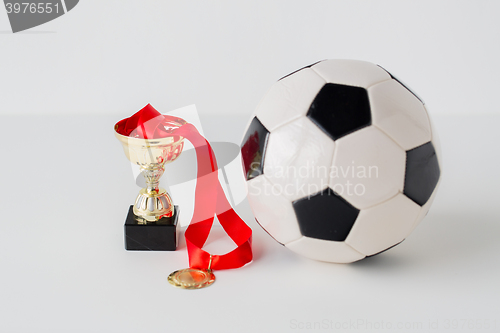 Image of close up of football ball, golden cup and medal