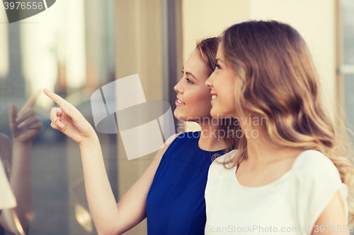 Image of happy young women pointing finger to shop window