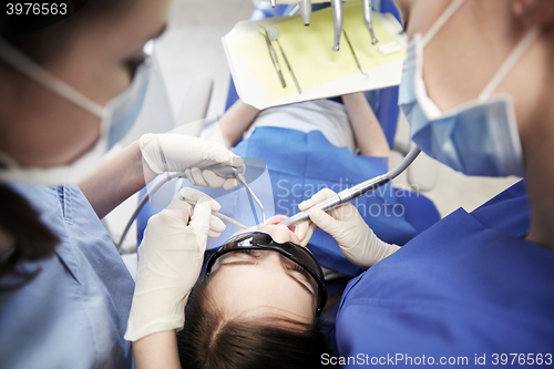 Image of female dentists treating patient girl teeth