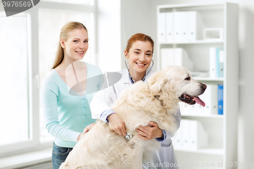 Image of happy woman with dog and doctor at vet clinic