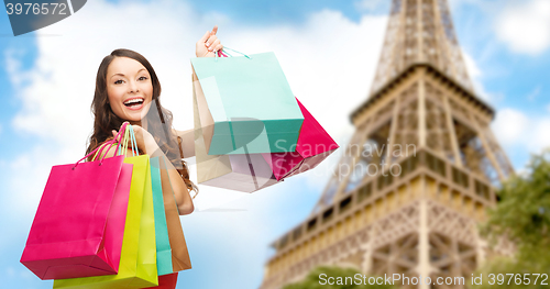 Image of happy woman with shopping bags over eiffel tower