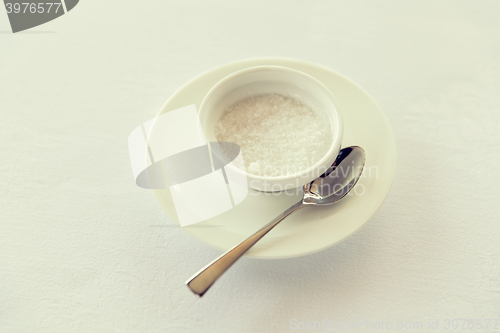 Image of sugar bowl and saucer with spoon on table