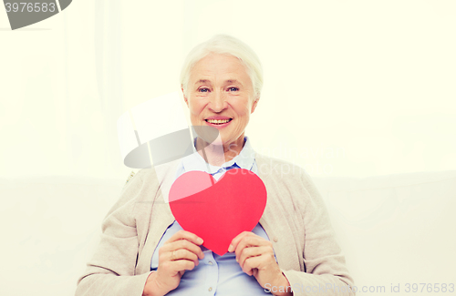 Image of happy smiling senior woman with red heart at home