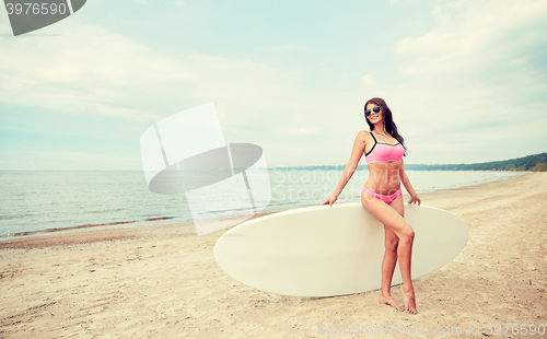 Image of smiling young woman with surfboard on beach