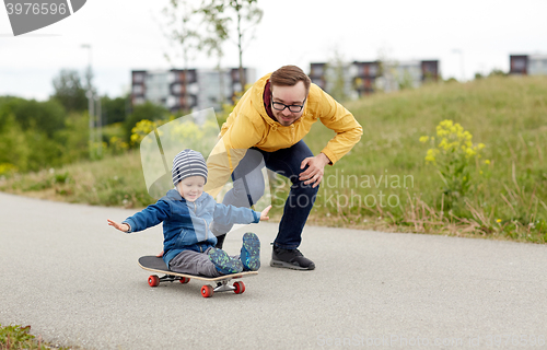 Image of happy father and little son riding on skateboard