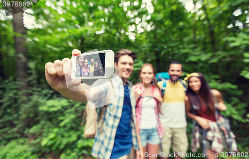 Image of friends with backpacks taking selfie by smartphone