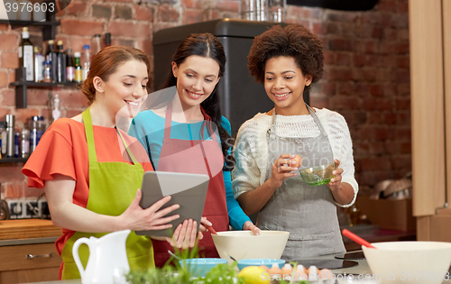 Image of happy women with tablet pc cooking in kitchen