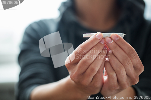 Image of close up of addict hands with marijuana joint