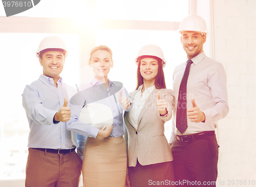 Image of happy business team in office showing thumbs up