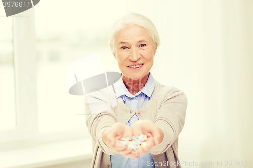 Image of happy senior woman with medicine at home