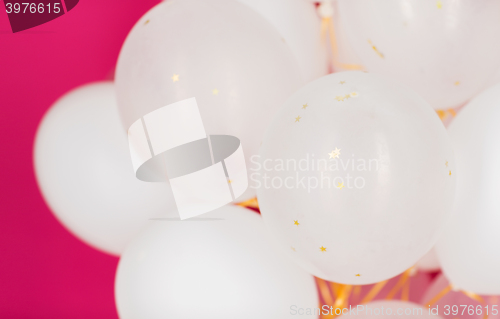 Image of close up of white helium balloons over pink