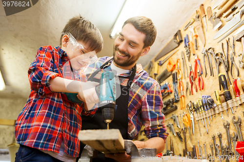 Image of father and son with drill working at workshop