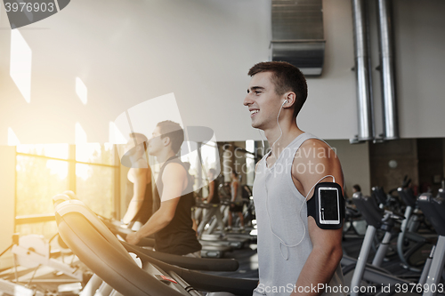 Image of man with smartphone exercising on treadmill in gym