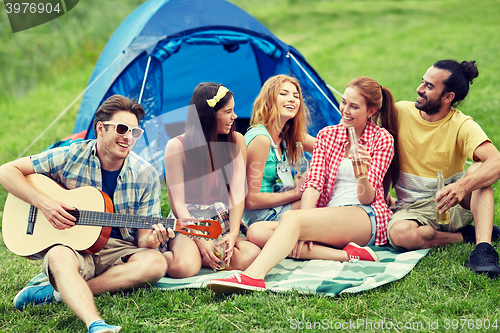 Image of happy friends with drinks and guitar at camping