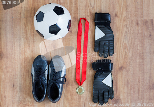 Image of close up of soccer ball, boots, gloves and medal