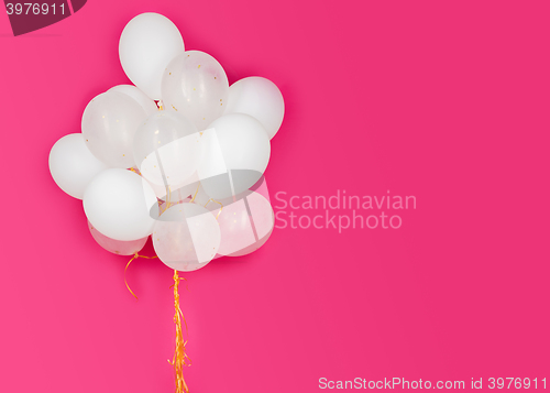 Image of close up of white helium balloons over pink