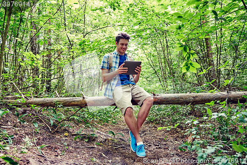 Image of happy man with backpack and tablet pc in woods