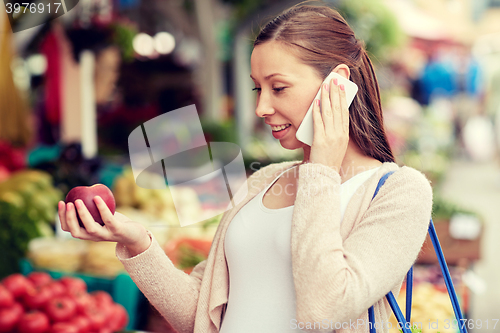 Image of pregnant woman calling on smartphone at market