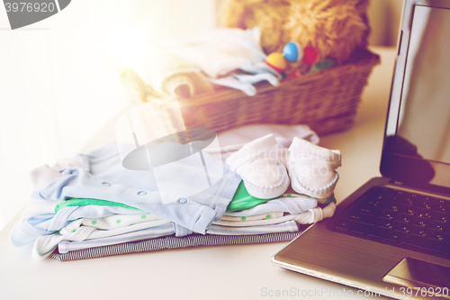 Image of close up of baby clothes, toys and laptop