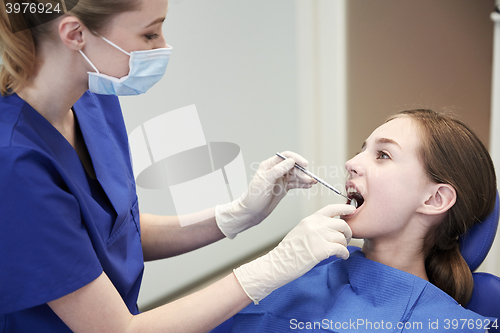 Image of female dentist checking patient girl teeth