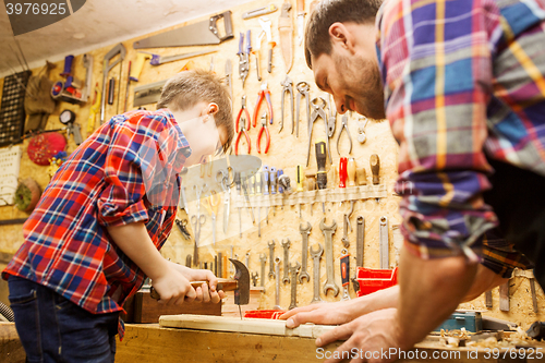 Image of father and son with hammer working at workshop