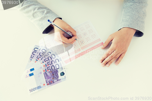 Image of close up of hands with lottery ticket and money