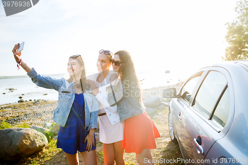 Image of happy women taking selfie near car at seaside